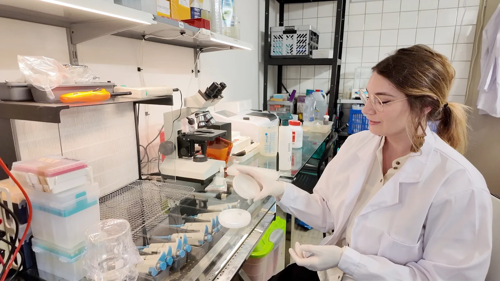 A Lambda Biolab member working at the bench with pipettes and a microscope